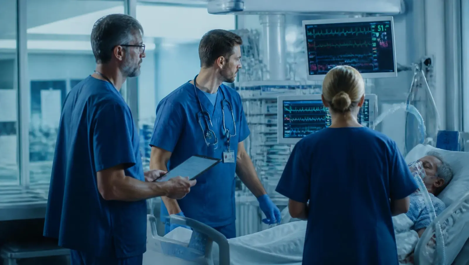 Intensive care team reviewing monitors beside a ventilated patient